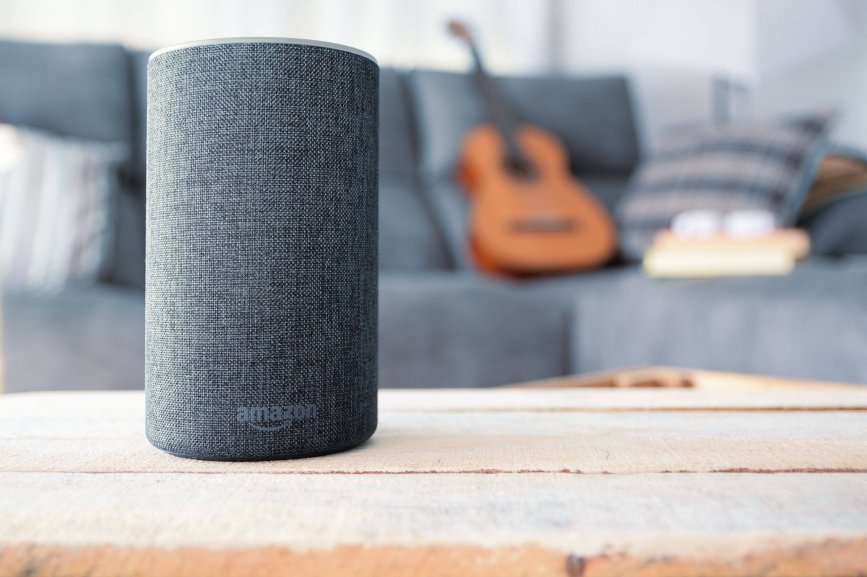Amazon Alexa smart speaker on a wooden table in a modern living room, enhancing smart home technology and automation.